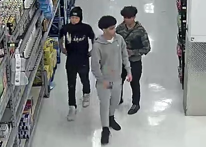 Vue de face des trois suspects qui se déplacent en groupe dans une allée du commerce.