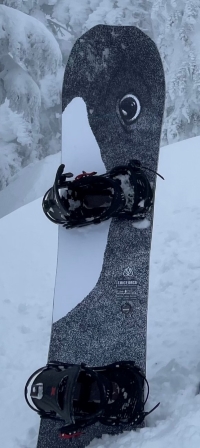 La planche à neige et les fixations volées. La planche à neige est noire et blanche et arbore l’image d’un épaulard.