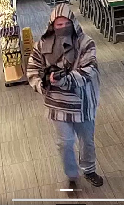 Male suspect pointing a black shotgun 